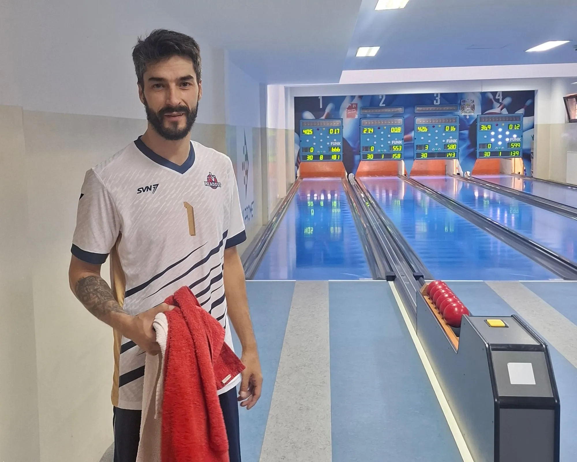 Miloš Simijonović se smeje sa peškirima u ruci, iza je semafor staze 1 sa zbirom 666.