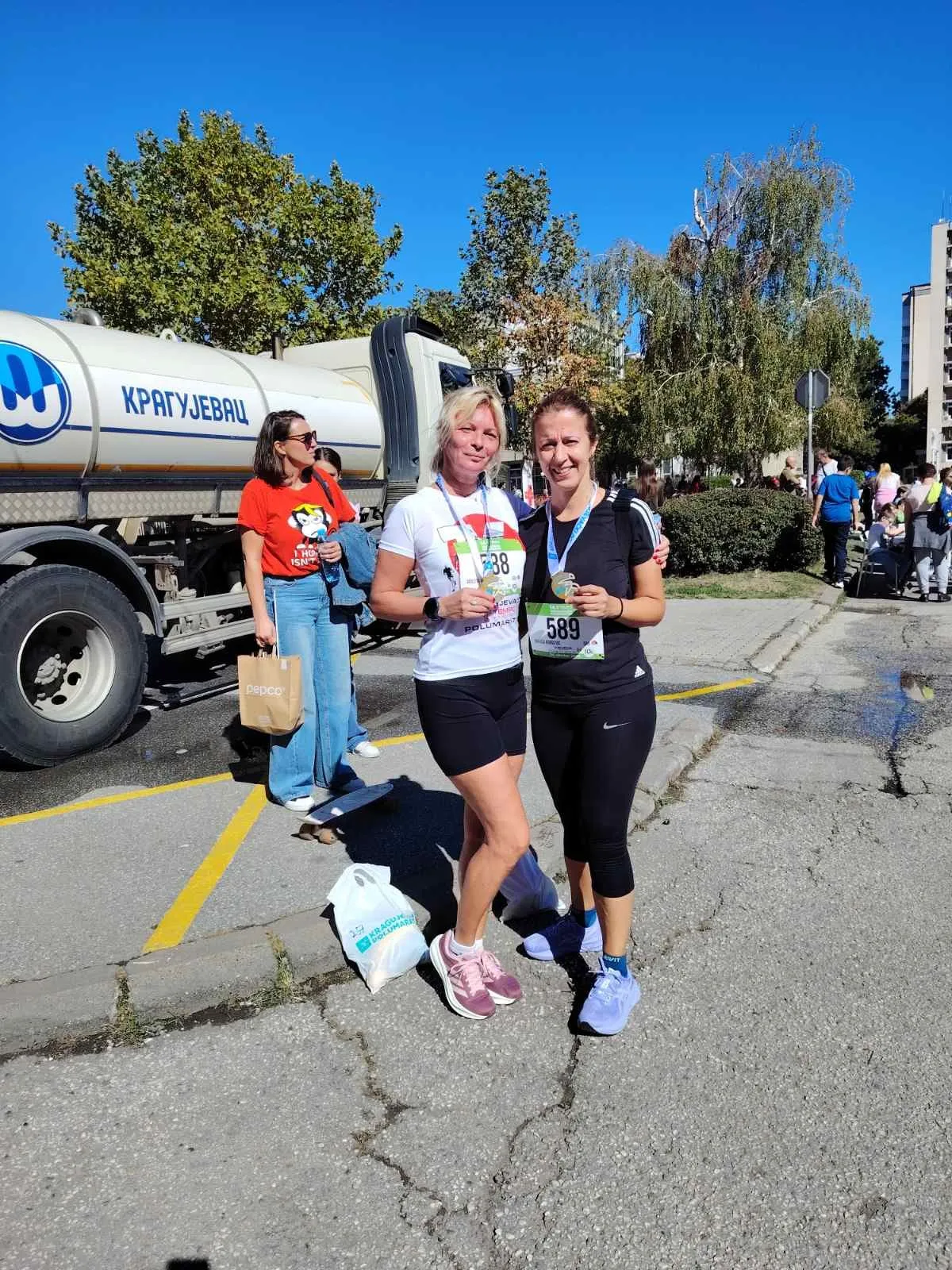 Violeta Mišić i Nataša Đorđević stoje zagrljene sa medaljama, iza je cisterna sa natpisom Kragujevac.