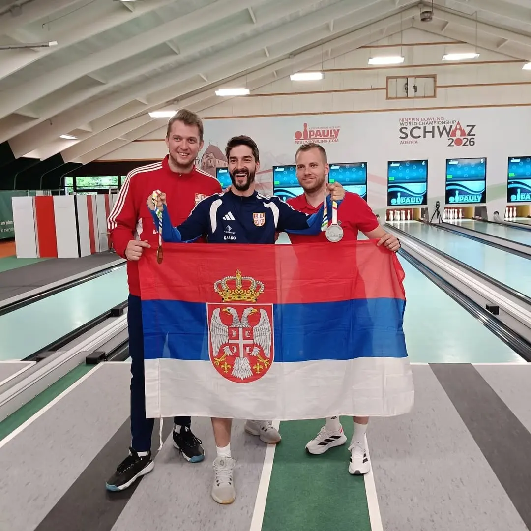 Tri reprezentativca Srbije drže državnu zastavu na kuglani svetskog prvenstva u Švacu, dvojica pokazuju medalje.