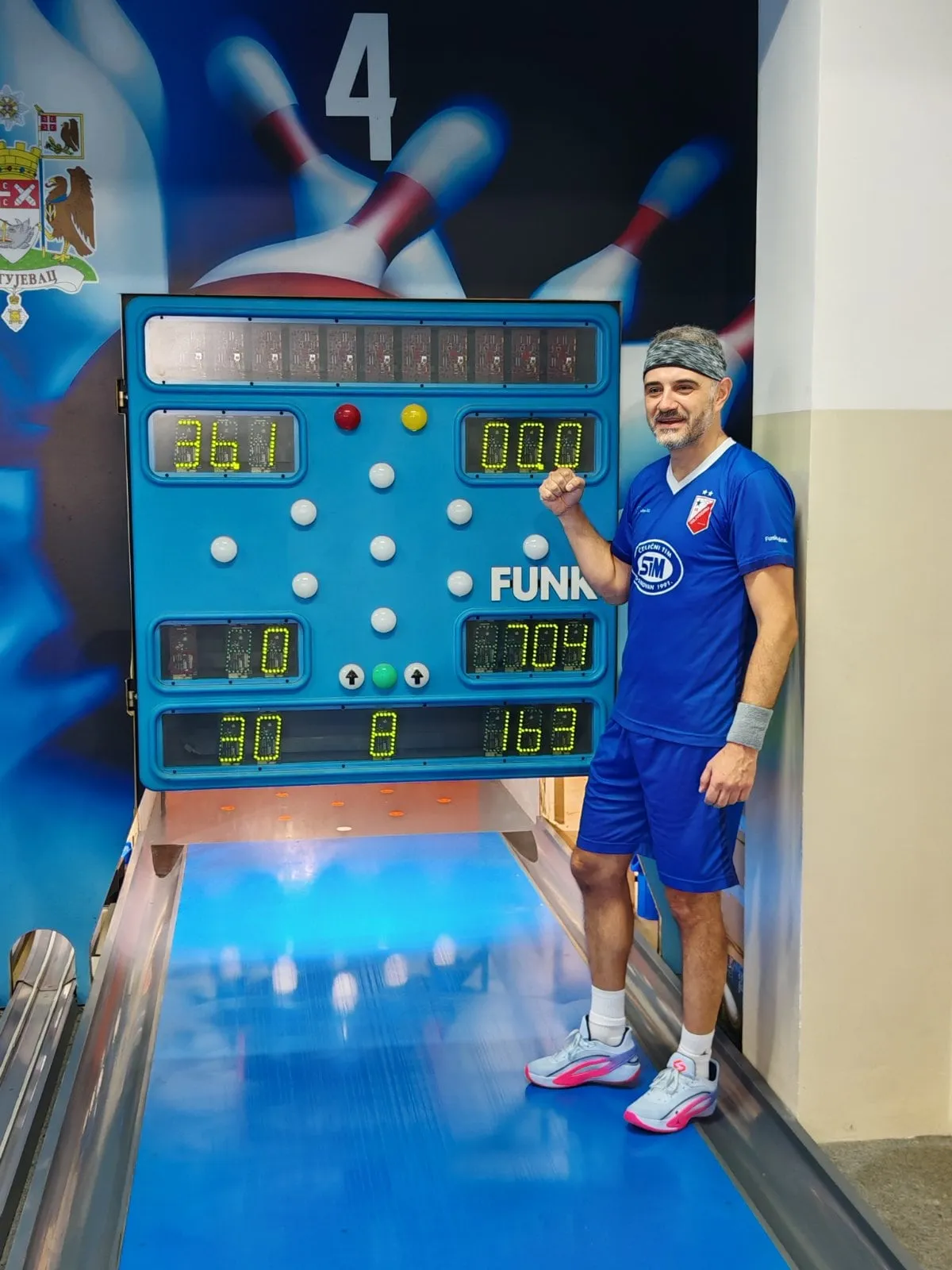 Igrač u plavoj majici Vojvodine sa trakom na glavi stoji pored semafora staze 4 na kome piše 704 i diže pesnicu.