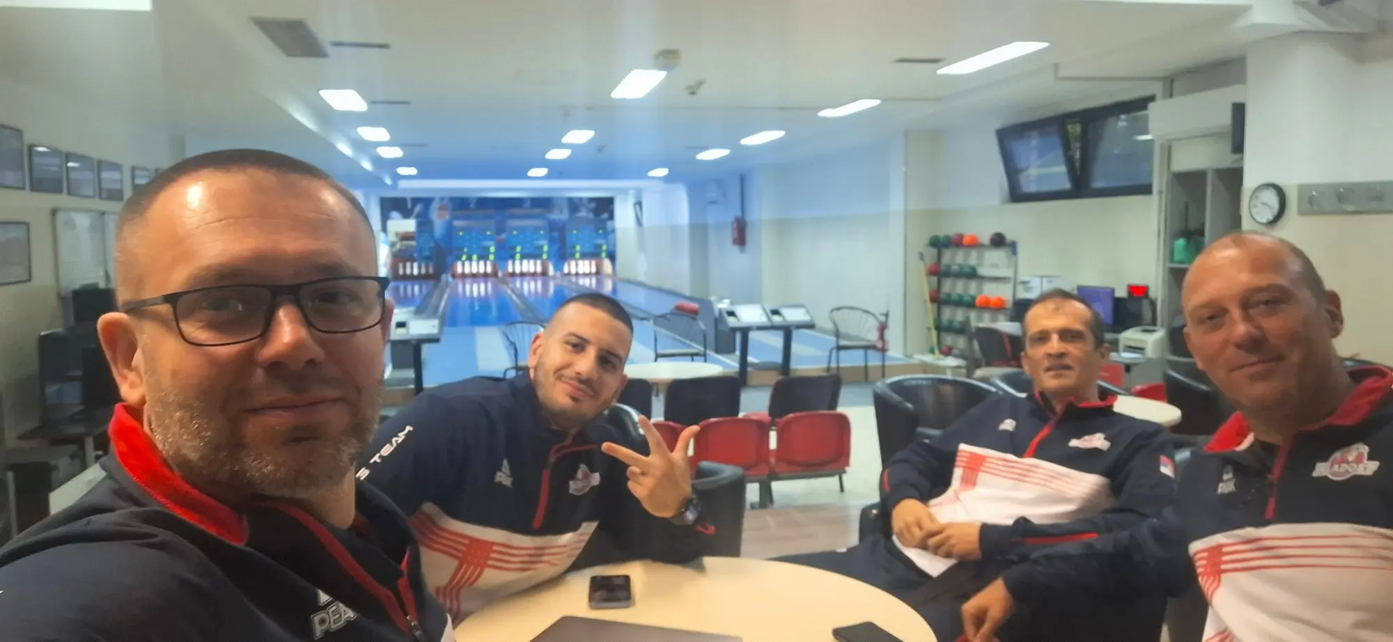 Selfi četvorice u trenerkama Mladosti za stolom u salonu, iza su staze i semafori.